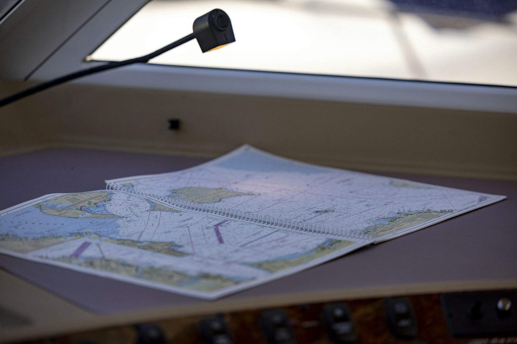 A nautical chart spread out on a chart table under a lamp