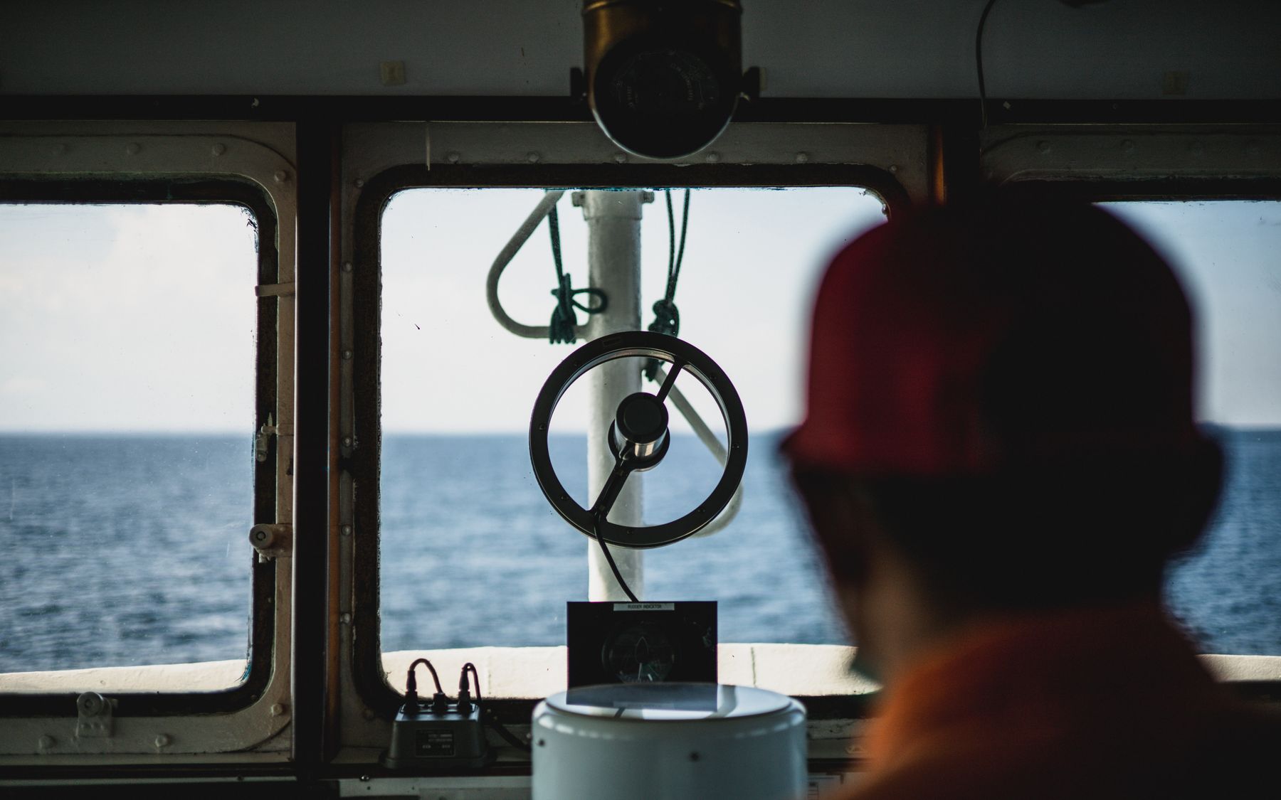 The view from a ship's bridge window, with a crew member seen from behind