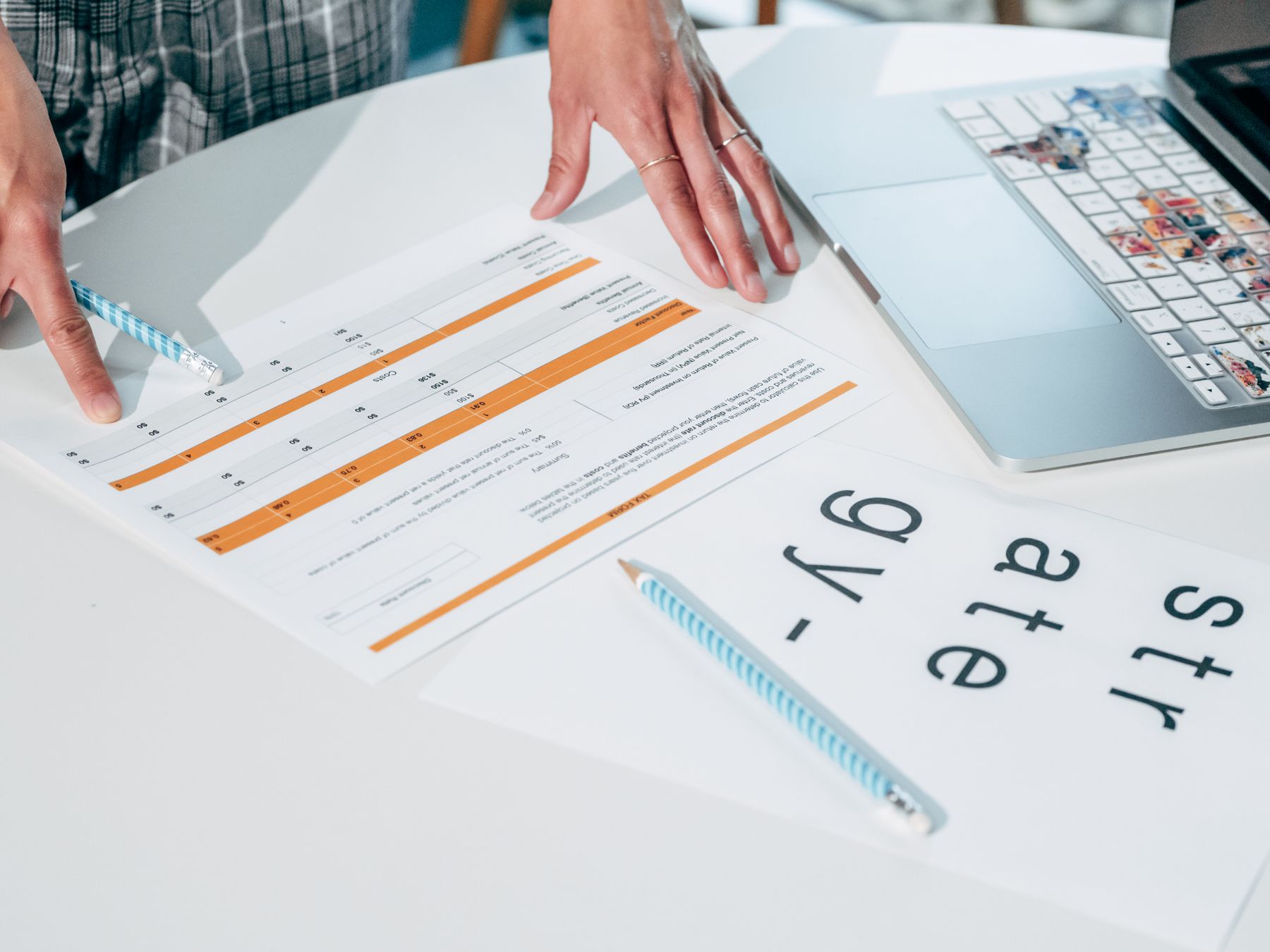 Hands reviewing printed plans and notes on a desk