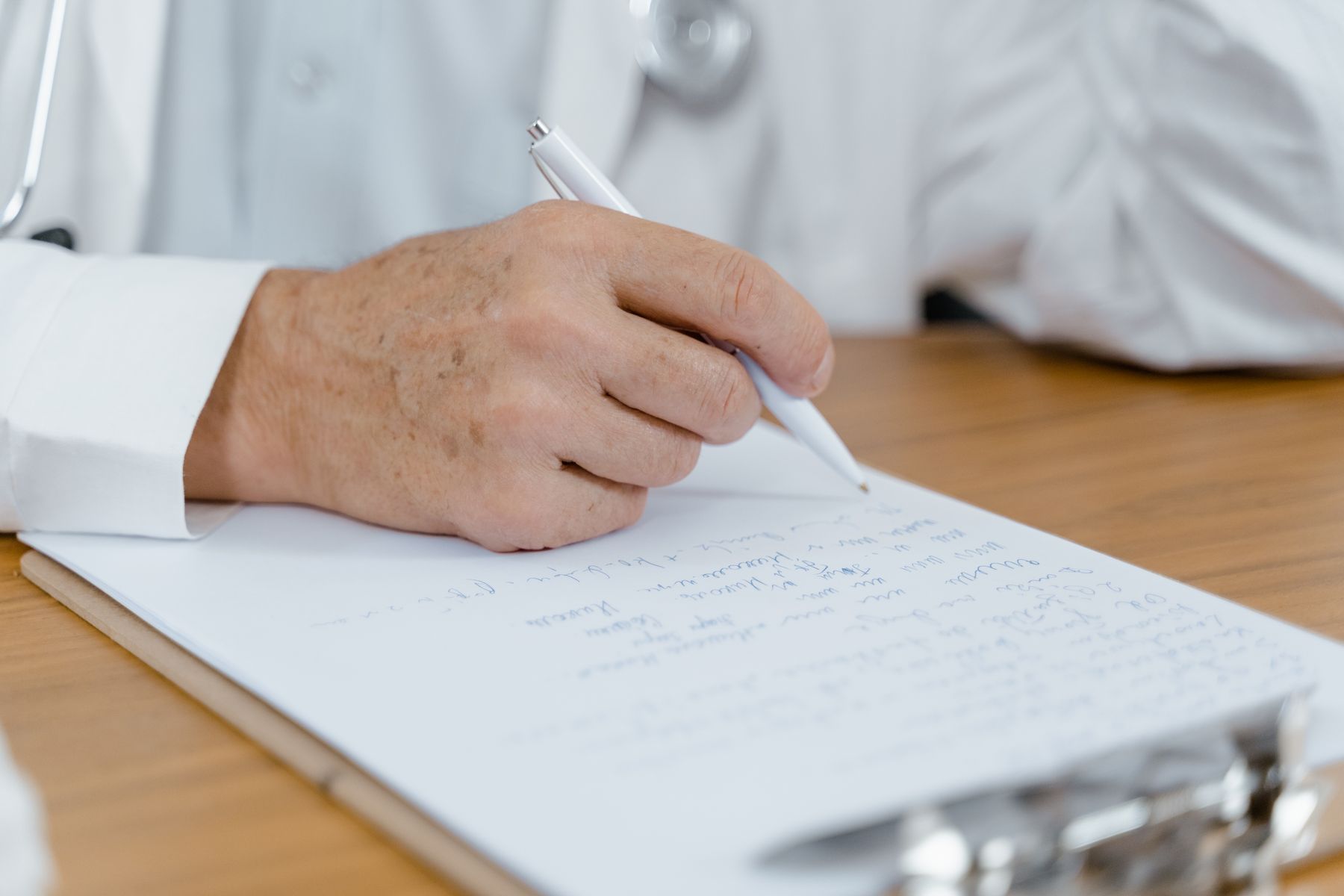 A doctor's hand writing notes with a pen