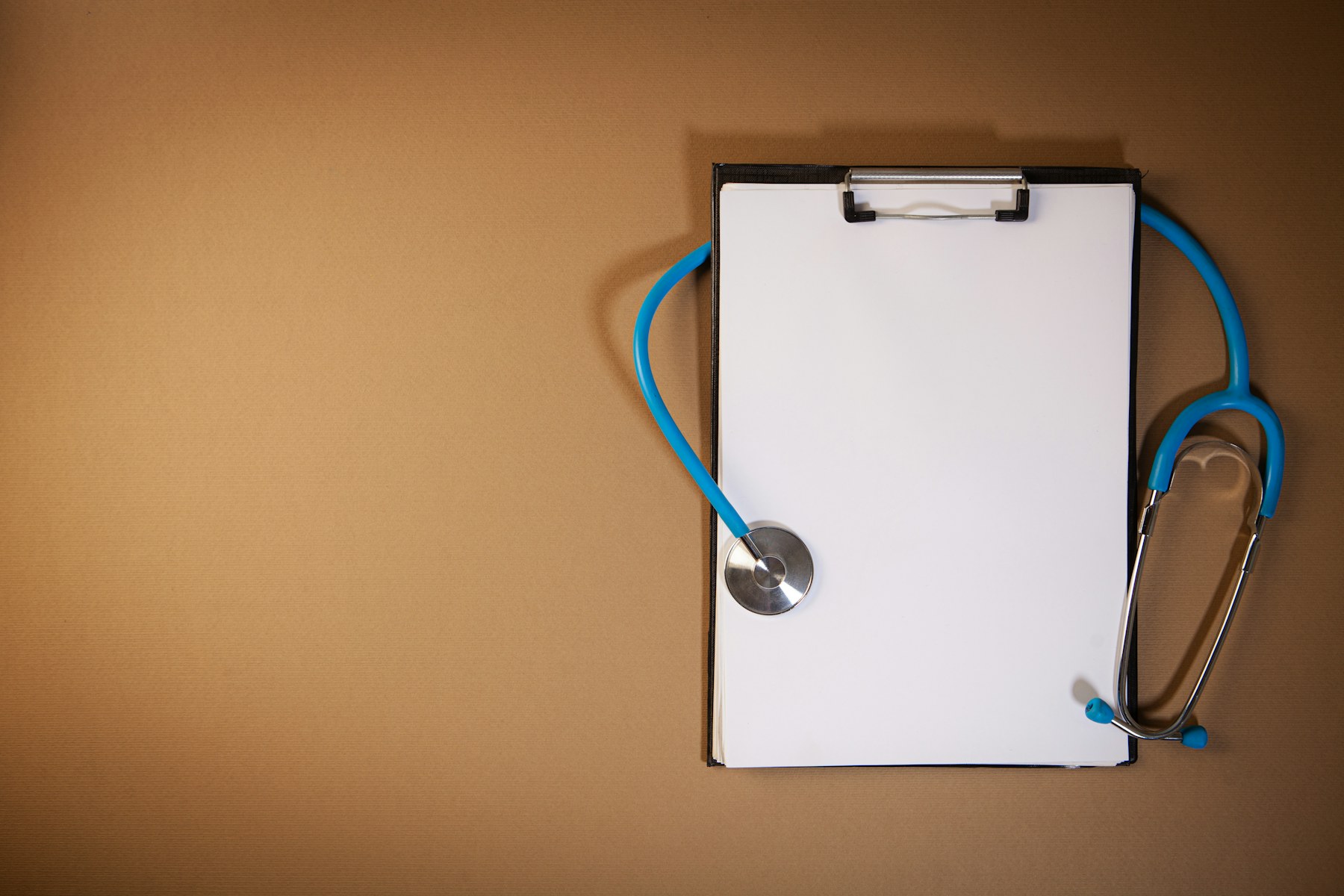 A clipboard and a stethoscope on a brown background