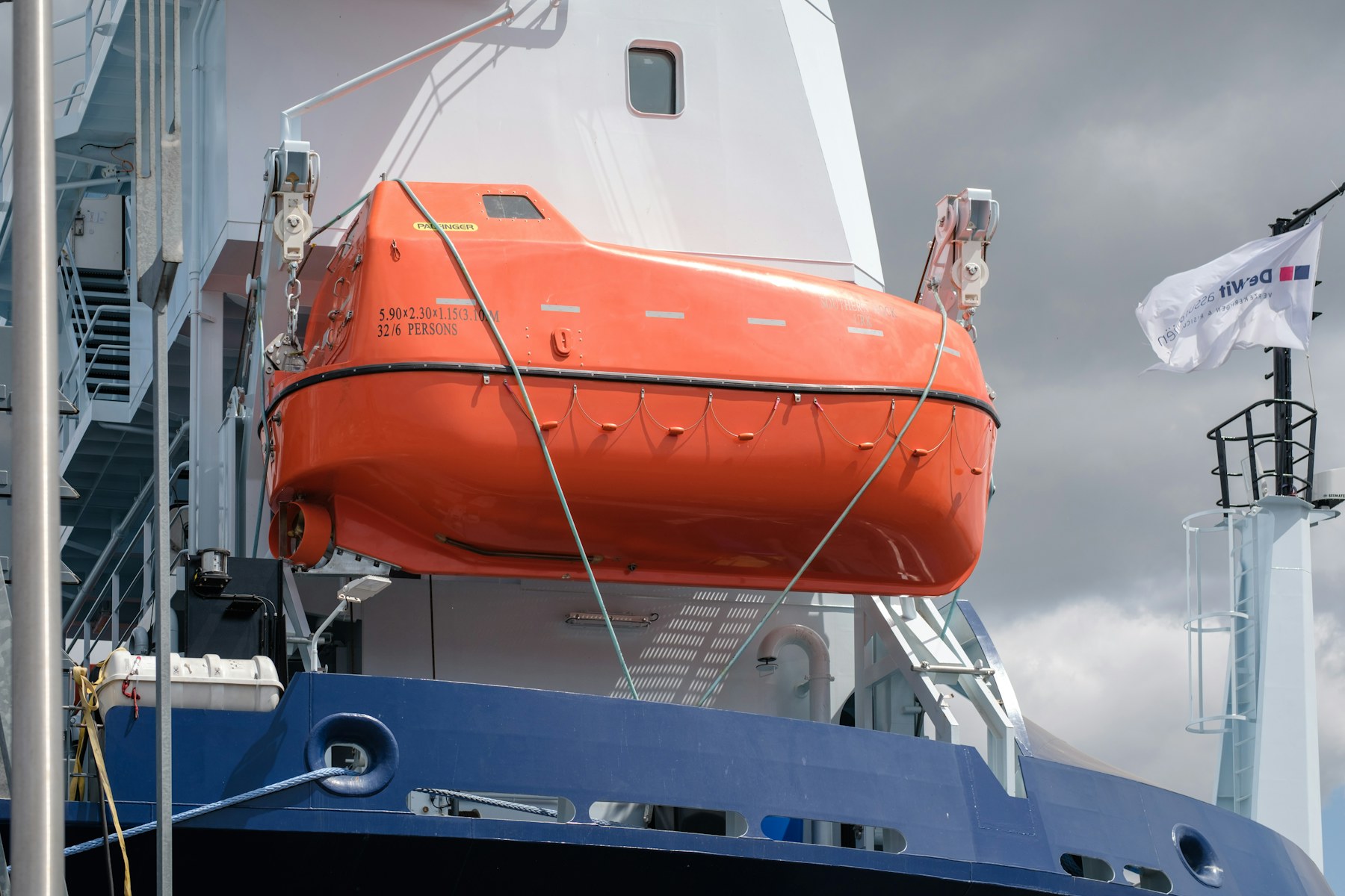 An orange lifeboat fixed to the side of a ship