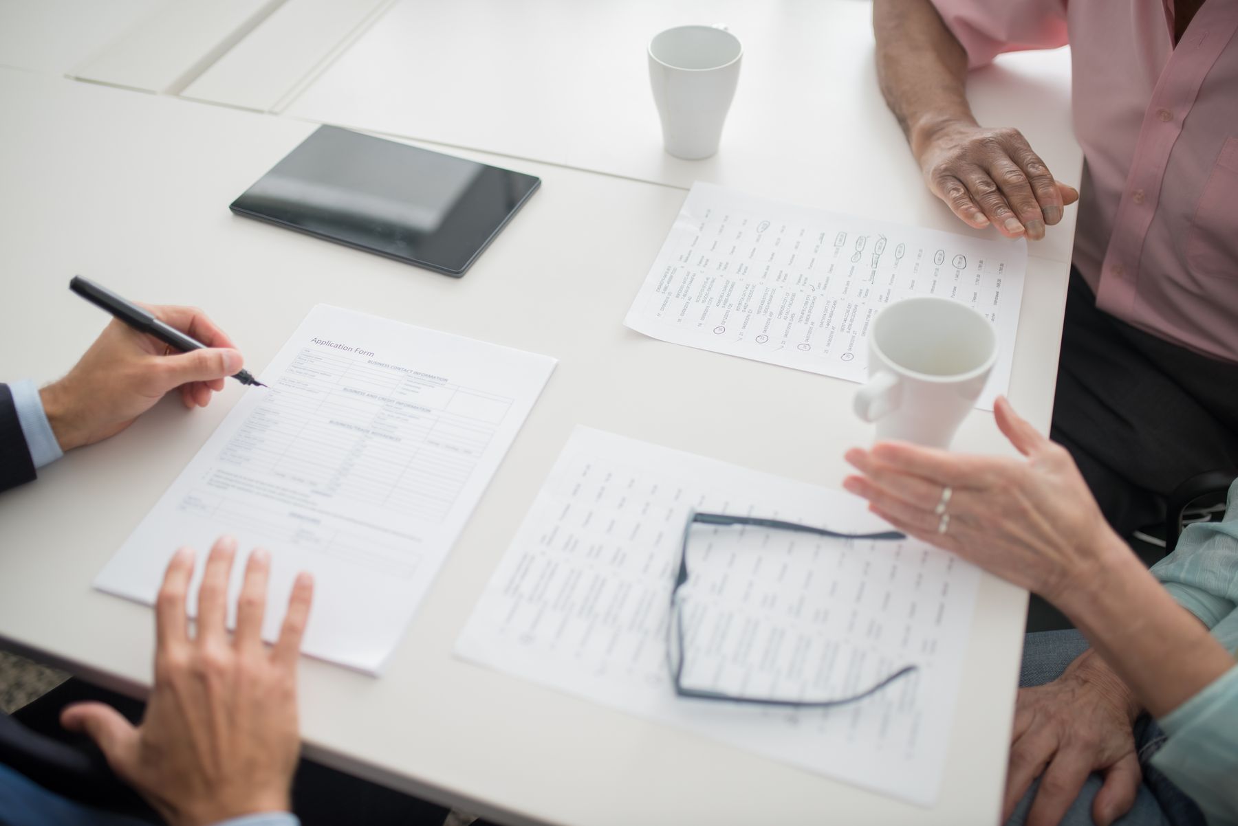 Hands writing on documents during a meeting