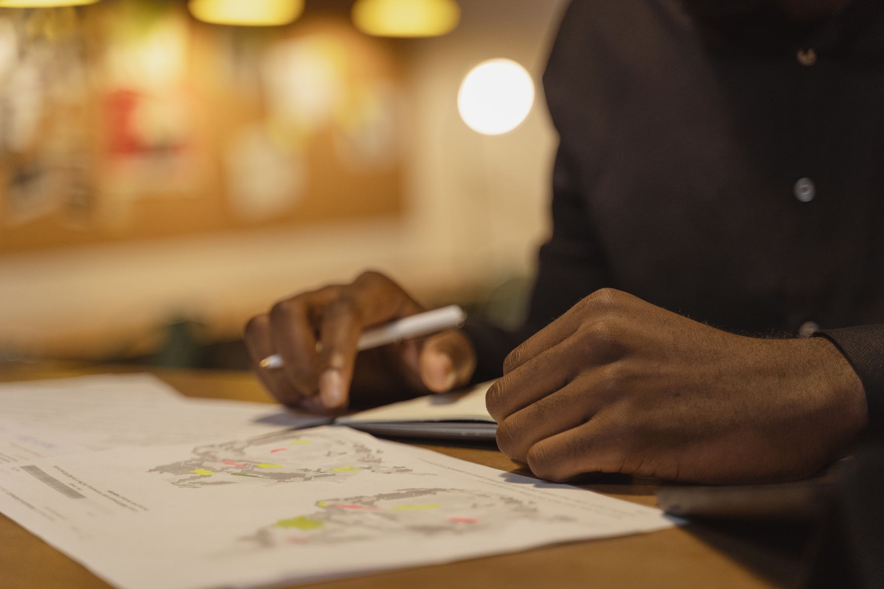 A person writing on papers at a desk in warm light