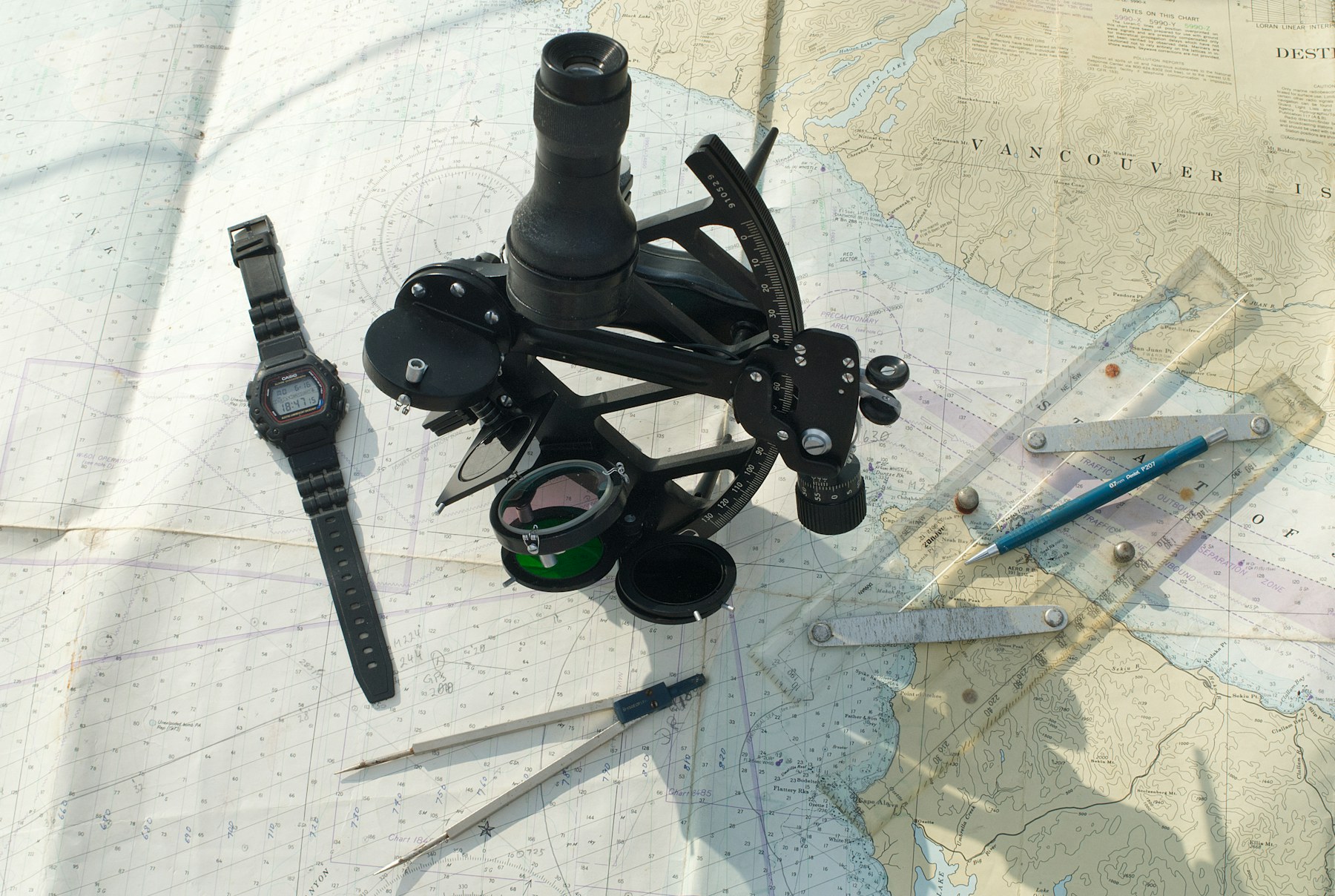 A sextant, watch, dividers and ruler on a nautical chart