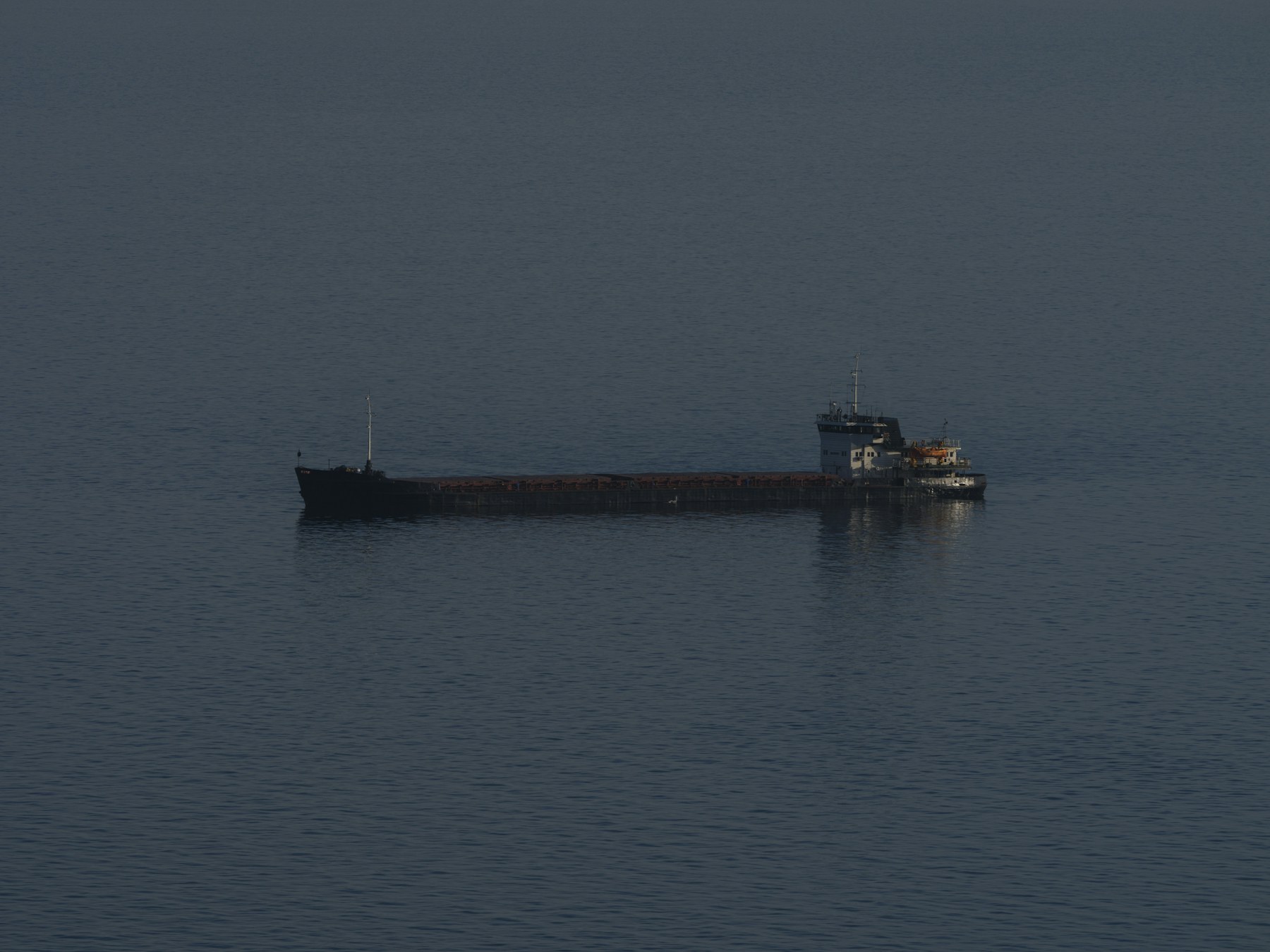 A cargo ship on a calm, dark blue sea