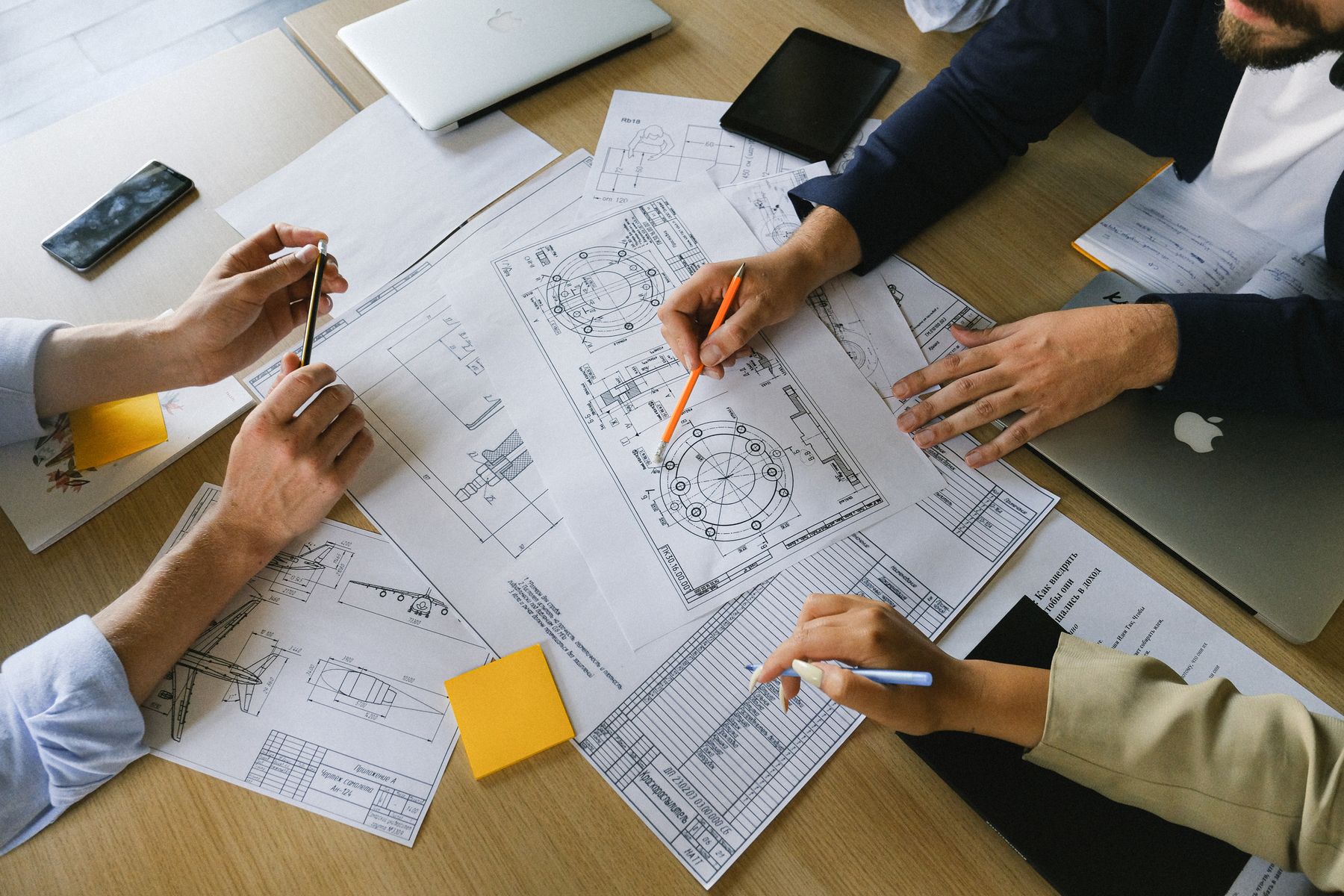 Colleagues' hands working through technical drawings and papers