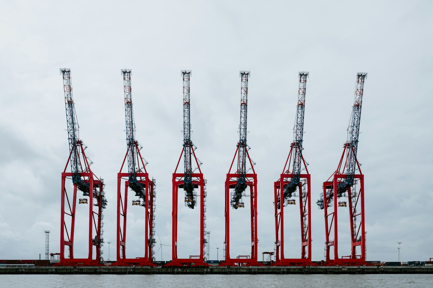 A row of red container cranes at a port