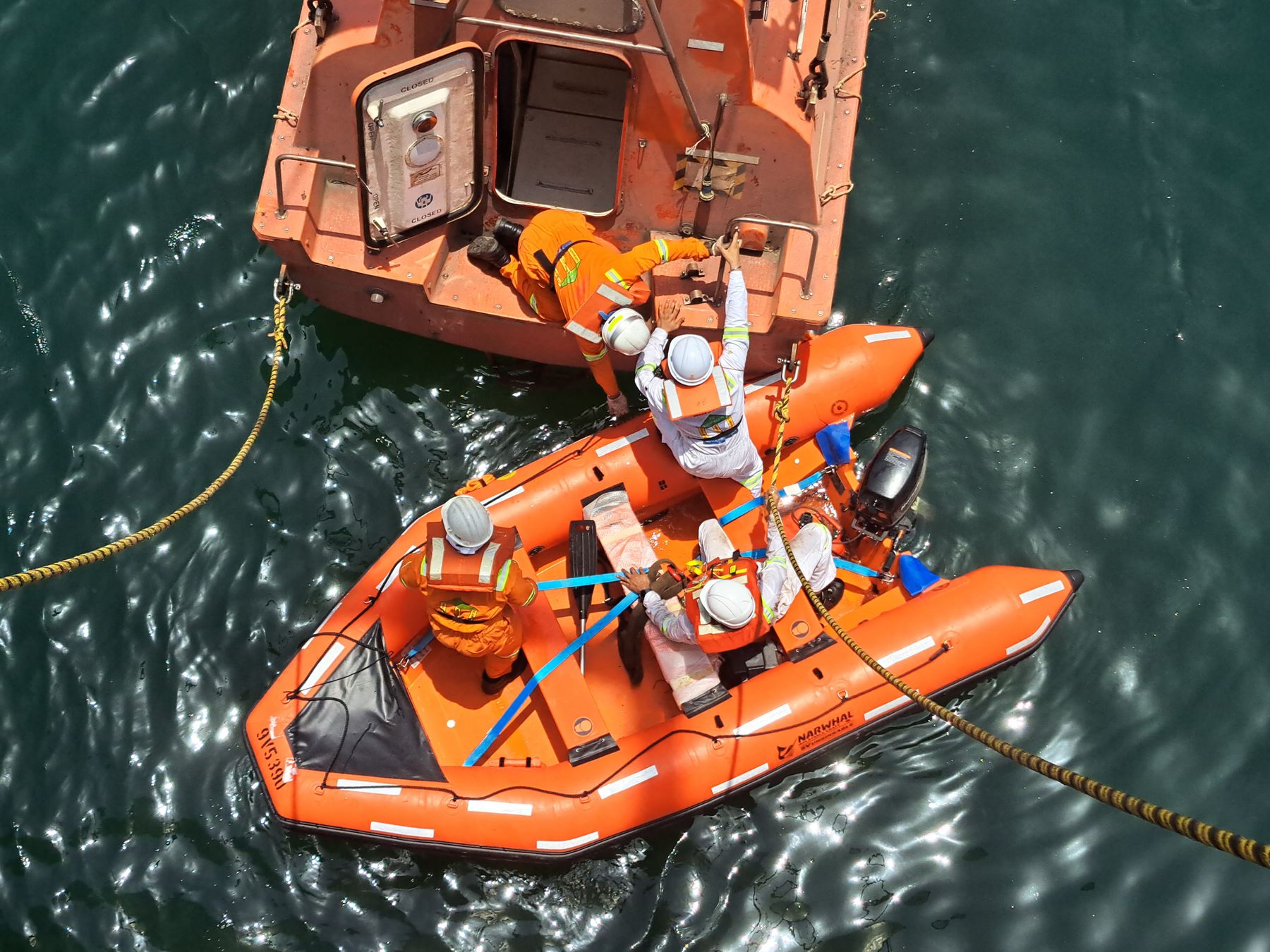 Crew in a lifeboat during a rescue training drill, seen from above